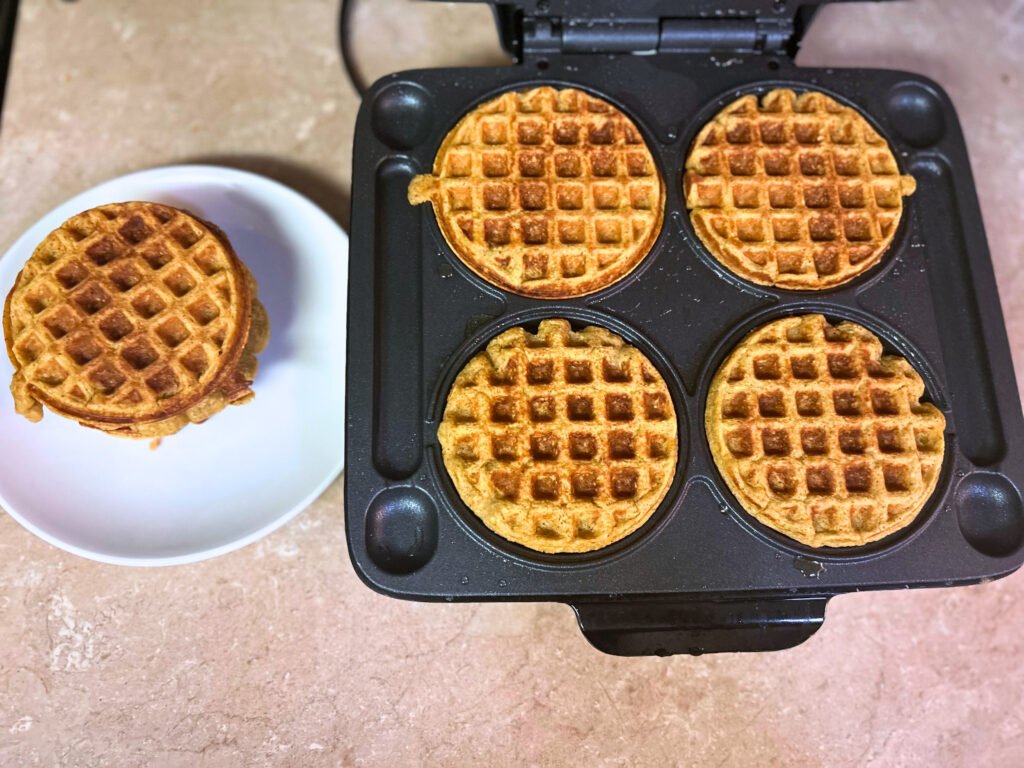 Fluffy healthy sweet potato waffles on a plate with maple syrup and fresh berries