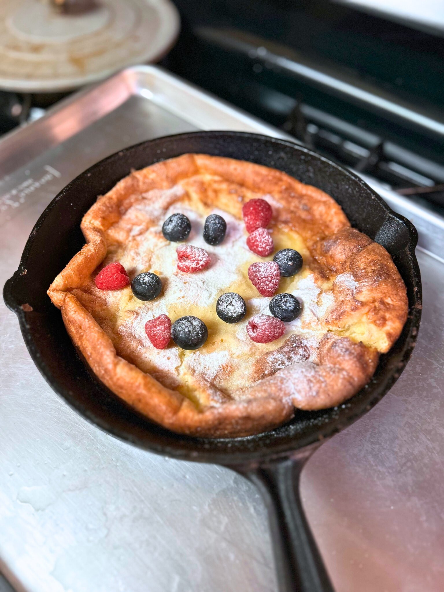 Easy fluffy sourdough German pancake dramatically puffed in a cast iron skillet