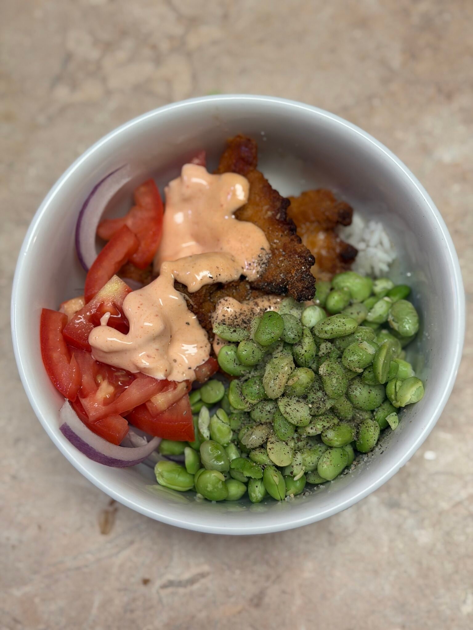 Easy weeknight rice bowl with grilled chicken, purple cabbage, cucumber, carrots, avocado, and sriracha mayo