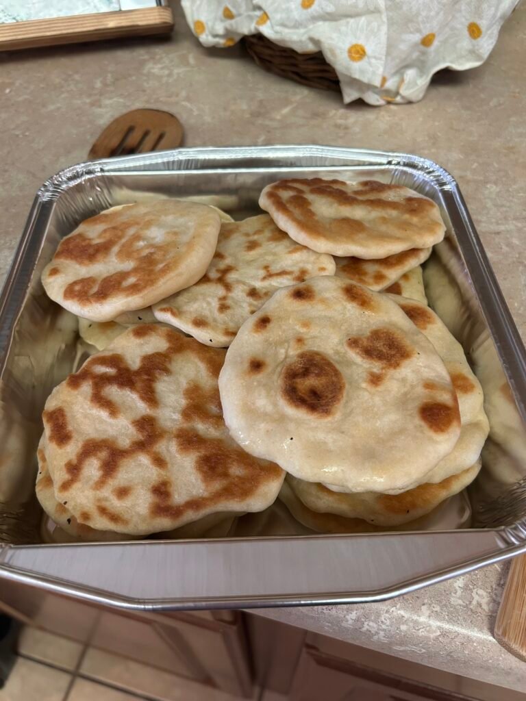 Stack of warm homemade sourdough discard naan flatbread on a plate