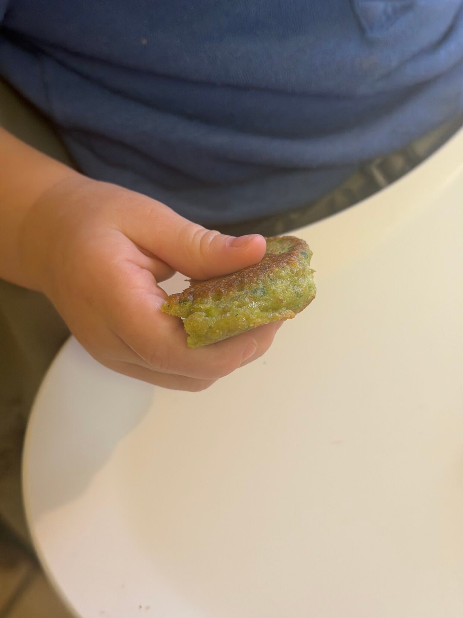 Edamame fritters cooking golden brown in a non-stick pan