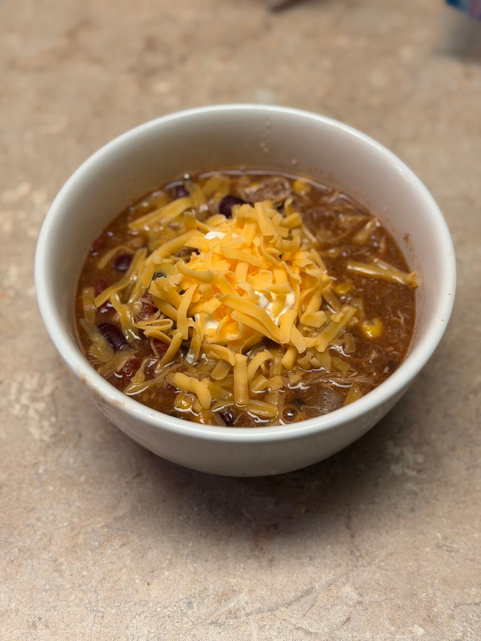 Bowl of easy homemade chicken tortilla soup topped with cheese and sour cream